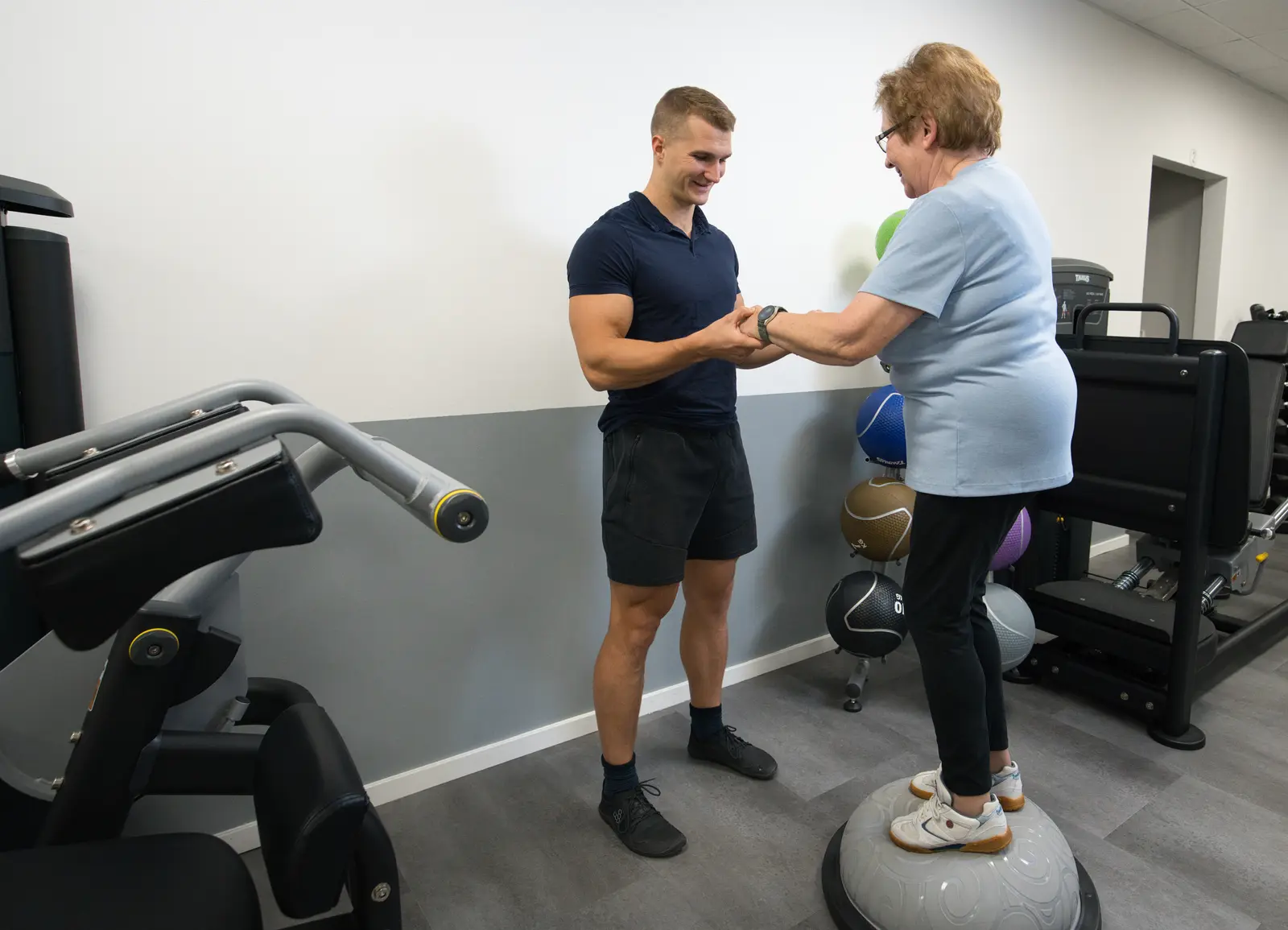 Henrik sichert eine ältere Kundin beim Balancetraining